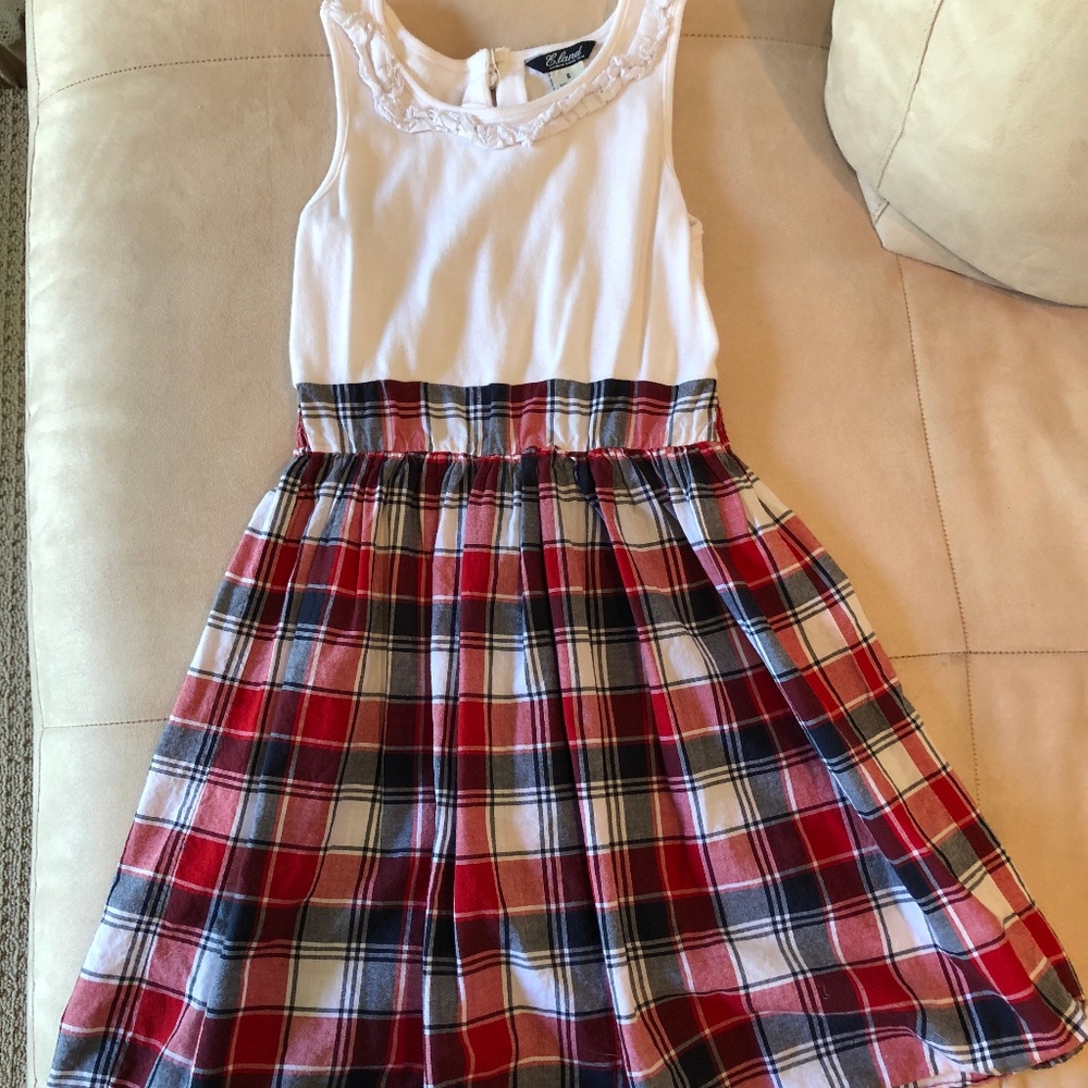 Sleeveless plaid dress with white ruffled top.